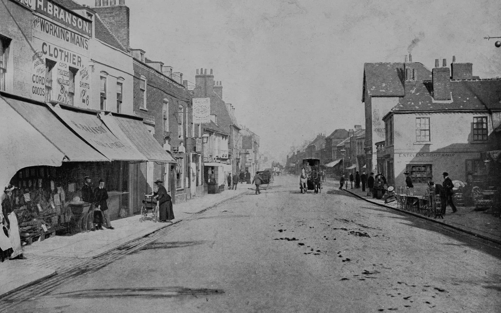Hounslow High Street in the late nineteenth century, with shopfronts and a horse-drawn carriage